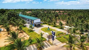 A hotel with a green roof, surrounded by palm trees and a landscaped garden. - ReeCha Mullai Resort (Iyakachchi)