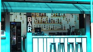 A bar with a variety of liquor bottles on shelves and stools in front. - ReeCha Mullai Resort (Iyakachchi)