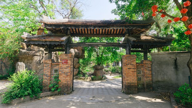 A traditional wooden gate with a tiled pathway leading through it. - SƠN HOME GARDEN HUE (Hue)