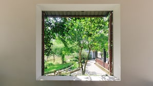 A window with a view of a garden, including trees and a brick wall. - SƠN HOME GARDEN HUE (Hue)