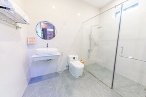 Un baño moderno con inodoro, lavamanos y cabina de ducha de vidrio.