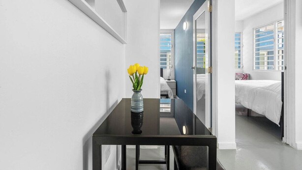 Et moderne hotelværelse med et sort bord, en vase med gule blomster og en seng med hvide sengetøj.