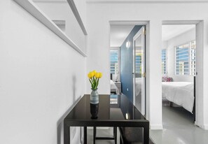 Een moderne hotelkamer met een zwarte tafel, een vaas met gele bloemen en een bed met wit beddengoed.