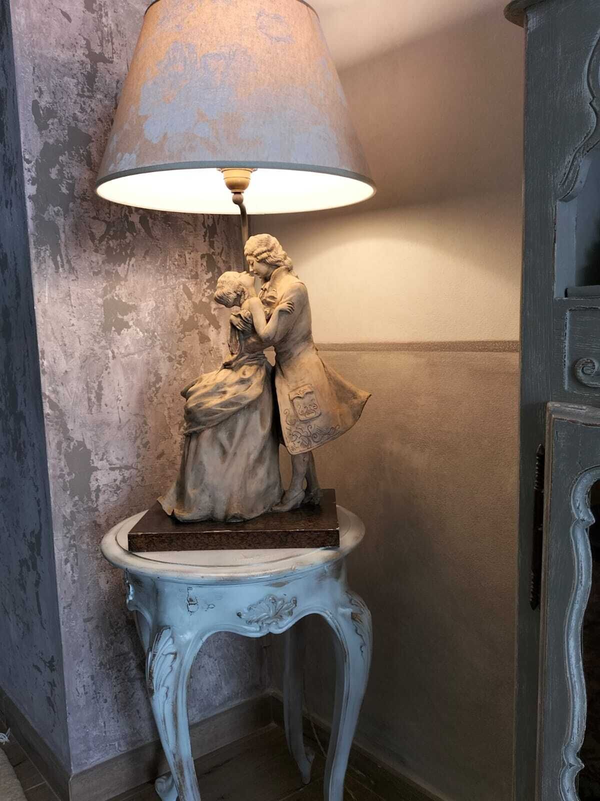 A statue of a woman and child on a pedestal with a lamp above it.