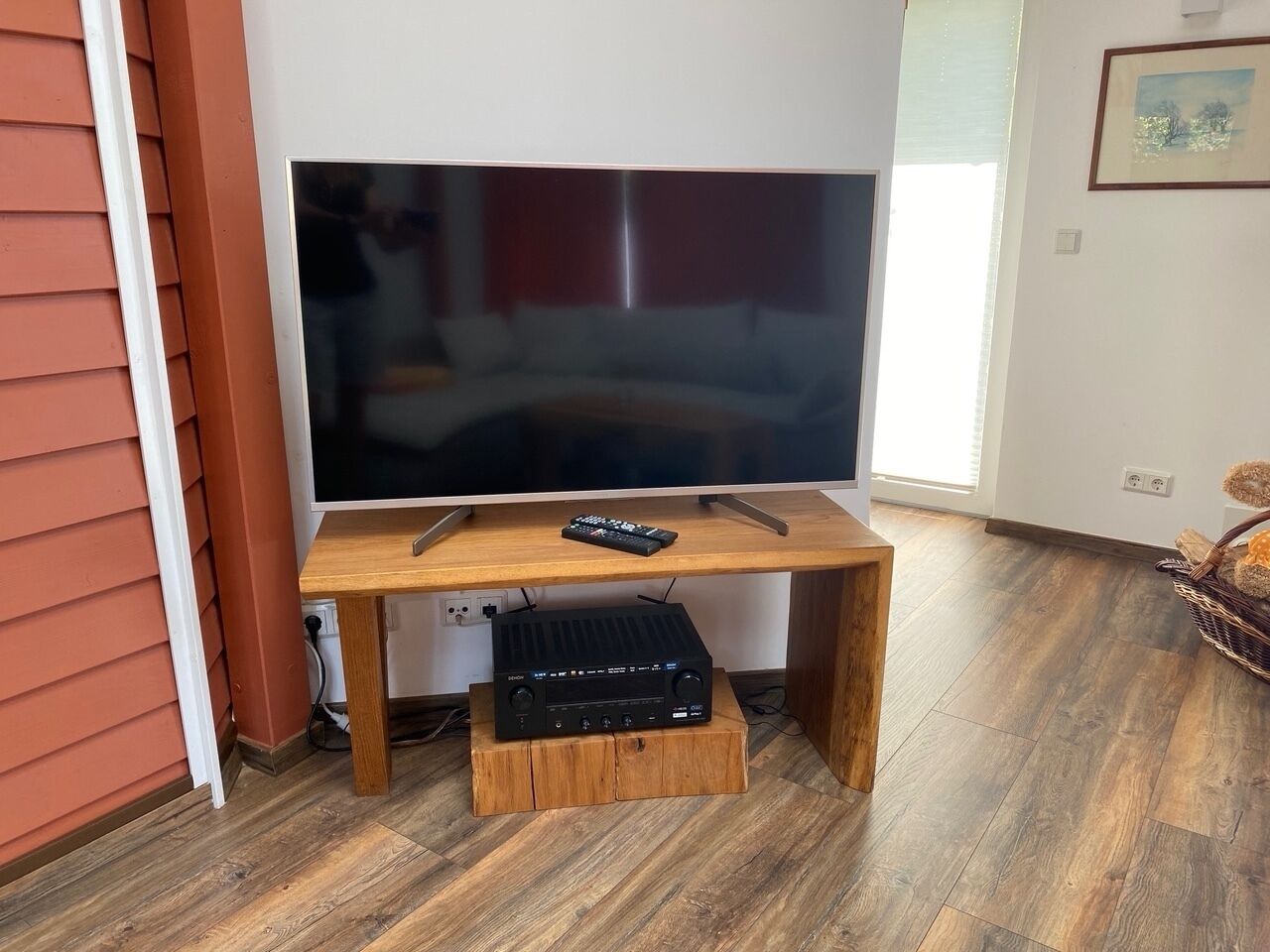 Un mueble bajo de madera para televisor con un televisor de pantalla plana, un control remoto y una barra de sonido.