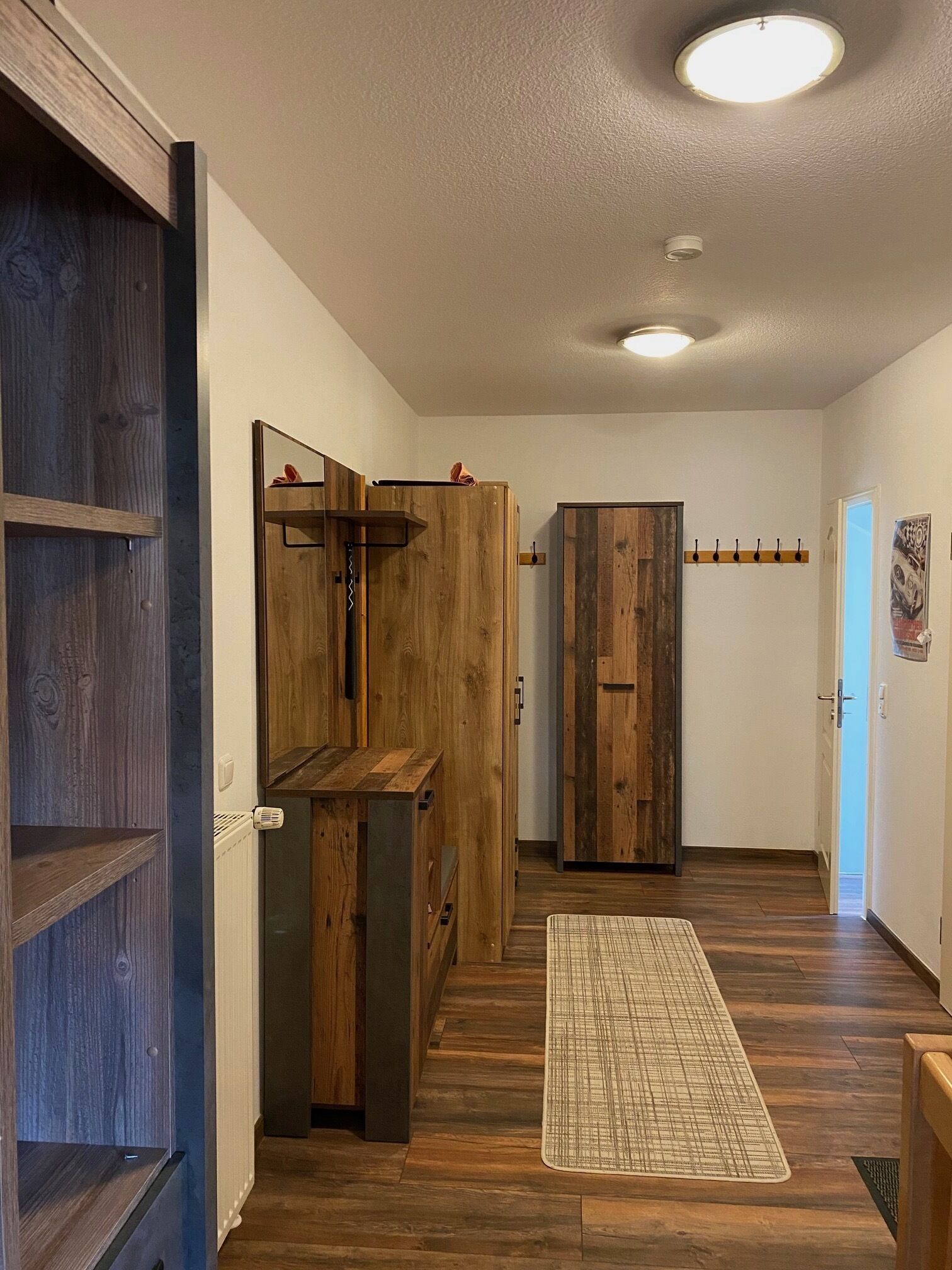 A hallway with wooden cabinets, a radiator, and a checkered mat.