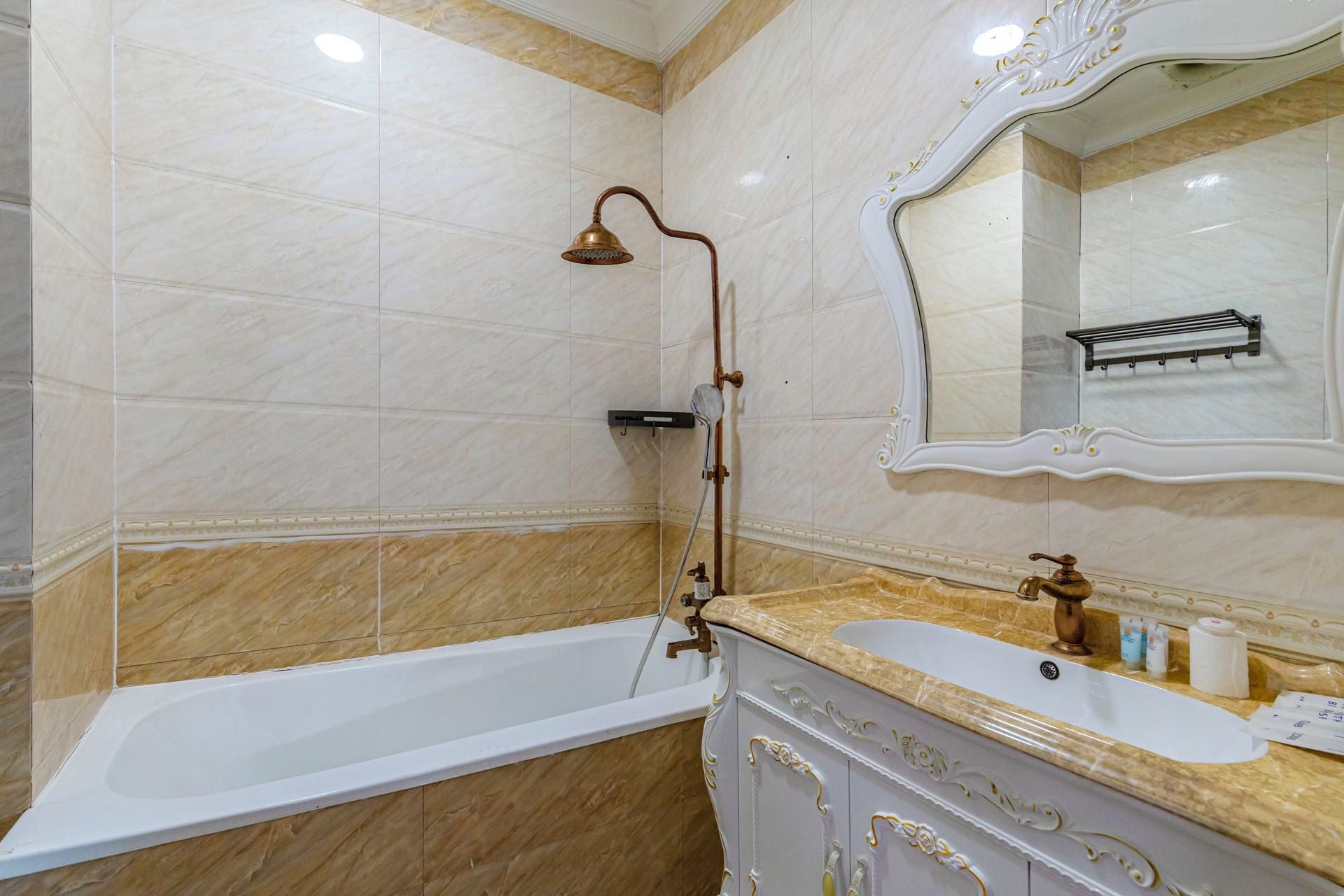 Un baño con bañera, ducha, lavamanos y espejo.