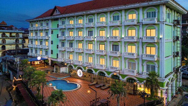 Un hotel de diversos pisos amb piscina, zona d'estar a l'exterior i façana ben il·luminada.