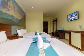 A hotel room with two beds, a painting on the wall, a television, and a desk with a coffee maker and water bottles. - Lisha roungnakhone hotel (Vang Vieng)