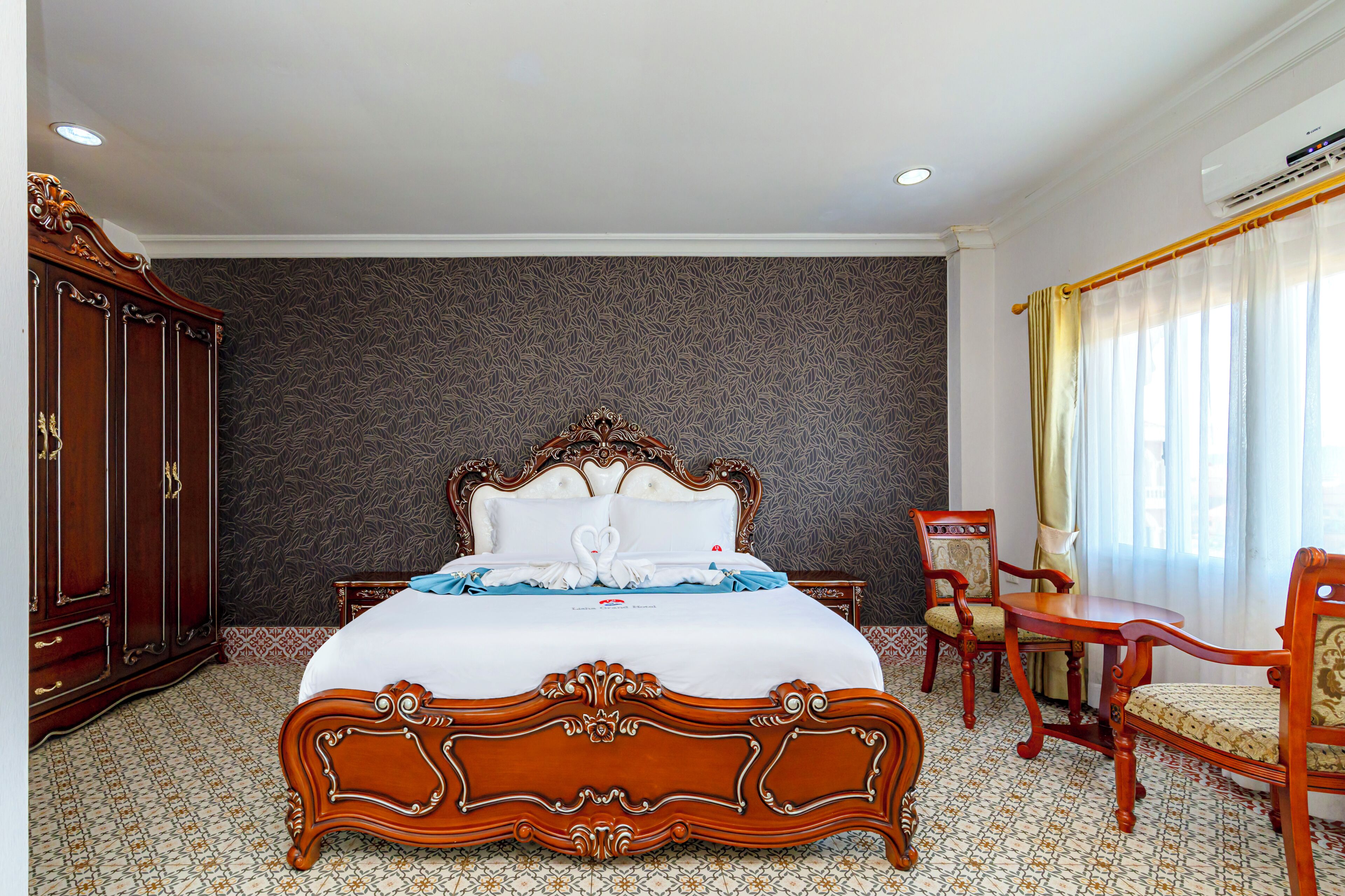 Una habitación de hotel con una cama grande, un armario de madera, un escritorio y una silla.