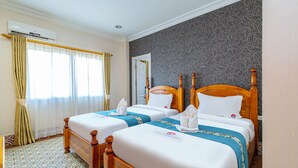 Une chambre d’hôtel avec deux lits en bois, un mur à motifs et une fenêtre avec des rideaux.