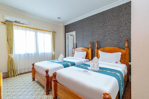 A hotel room with two wooden beds, a patterned wall, and a window with curtains. - Lisha roungnakhone hotel (Vang Vieng)