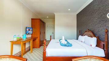 A hotel room with a bed, a desk, a television, and a wardrobe.