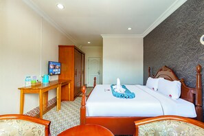 A hotel room with a bed, a desk, a television, and a wardrobe.