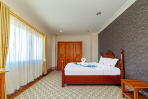 A hotel room with a bed, a wooden wardrobe, a patterned floor, and a window with curtains. - Lisha roungnakhone hotel (Vang Vieng)