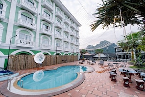 A hotel with a swimming pool, outdoor seating, and a view of mountains. - Lisha roungnakhone hotel (Vang Vieng)