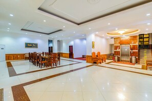 Eine großzügige Lobby mit Marmorboden, Holzmöbeln und einem Empfangsbereich mit Marmor-Theke und Aufzug.