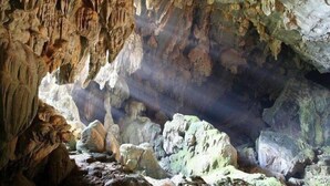 Interior d'una cova amb estalactites i estalagmites, formacions rocoses naturals i un terreny accidentat.