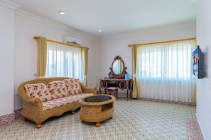 A room with a sofa, a small table, a mirror, and a television mounted on the wall. - Lisha roungnakhone hotel (Vang Vieng)