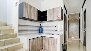 A modern kitchen with a built-in stove, a sink, and a blue water dispenser. - Hotel O Ada Residence (Karawang)