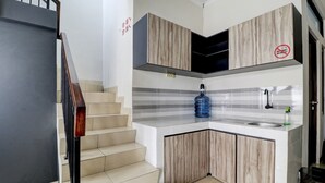A modern kitchen with a corner island, a built-in stove, and a stainless steel sink. - Hotel O Ada Residence (Karawang)