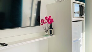 A modern living room with a flat-screen TV mounted on the wall, a white cabinet below, and a microwave on the right. - Apartment for 2 in Nerja center (Nerja)