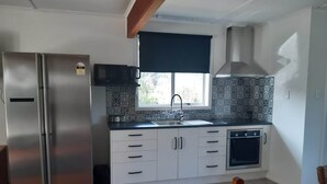 A compact kitchen with a stainless steel refrigerator, a microwave, a sink, and a stove.