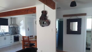 A modern kitchen with white cabinets, a black countertop, and a hanging light fixture.