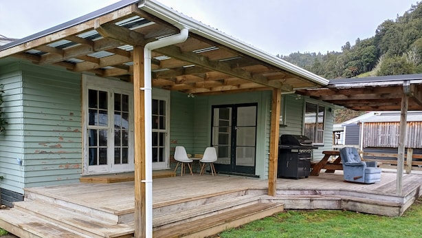 A wooden deck with a covered porch, a grill, and two chairs.