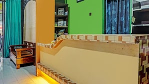 Un espace d’accueil doté d’un sol carrelé, d’un banc en bois et d’un comptoir orné d’une bordure de carreaux décoratifs.