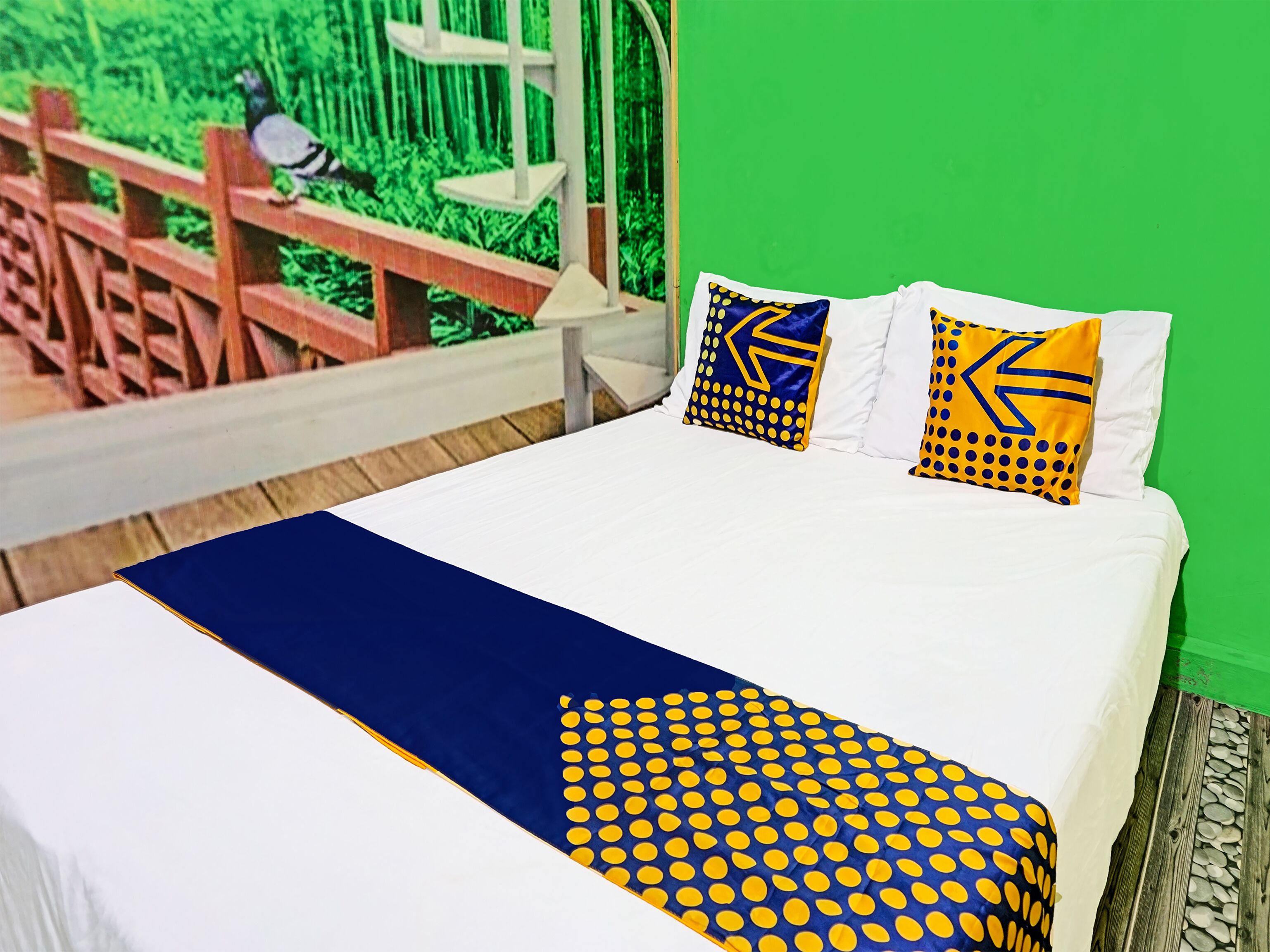 A bed with white bedding, two pillows with blue and yellow patterns, and a blue and yellow blanket.