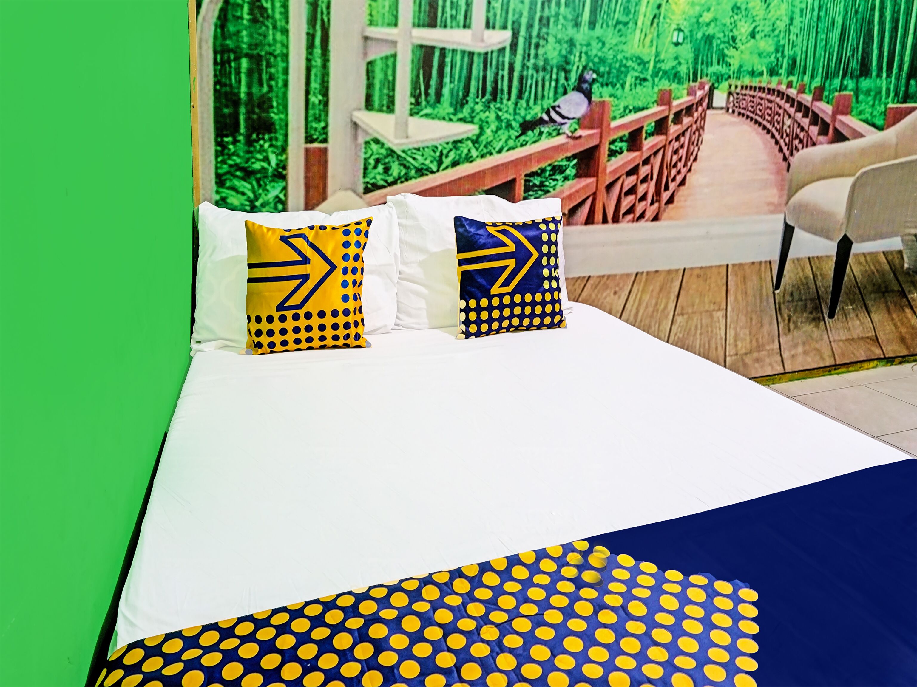A bed with white bedding and two pillows with yellow and blue patterns.