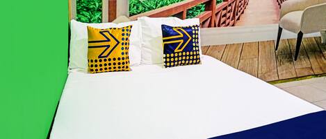 A bed with white bedding and two pillows with yellow and blue patterns.
