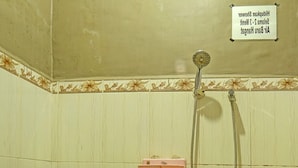 Une salle de bain équipée de toilettes, d’une douche et d’un panneau indiquant le numéro de la chambre et l’étage.