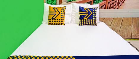 Una cama con ropa de cama blanca y dos almohadas con diseños azules y amarillos.