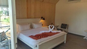 Un dormitorio con cama, mesita de noche, lámpara de pared y ventana.