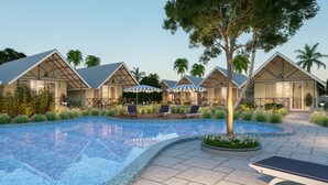 Un resort con varias cabañas, una piscina central y zonas de estar al aire libre.