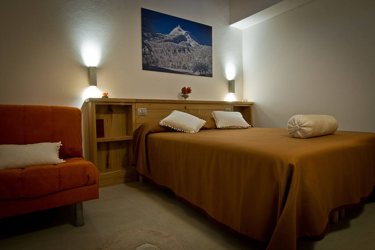 A bedroom with two beds, a wooden headboard, a nightstand, and a red chair.