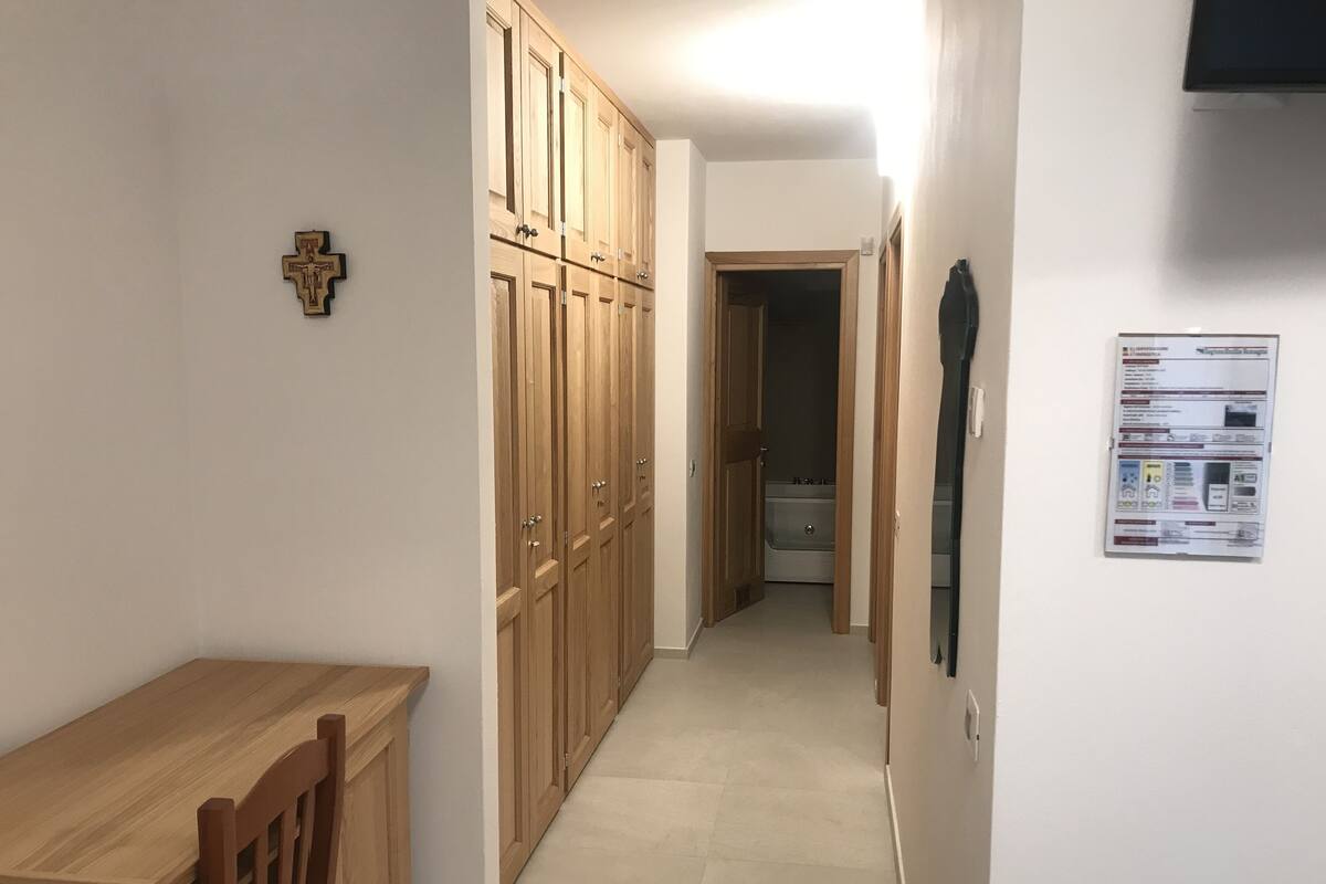 A hallway with wooden cabinets, a wooden table, and a cross on the wall.