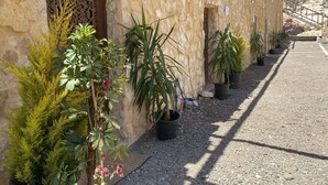 Un edificio de piedra con camino de grava y plantas en macetas a lo largo de un lado.
