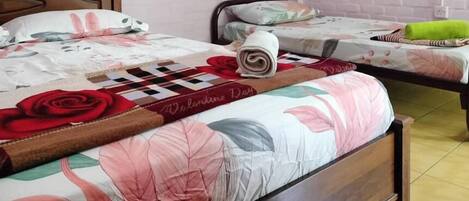 A neatly made bed with a floral bedspread, a rolled towel, and a book titled "Valentine's Day".