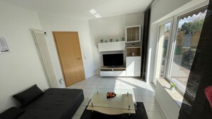 Un salon moderne avec un canapé, une table basse en verre et un téléviseur.
