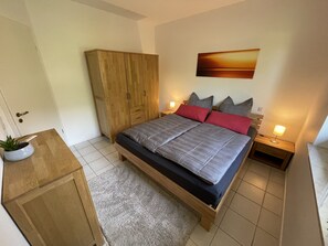 A bedroom with a bed, bedside tables, a wardrobe, and a painting on the wall. - Gemütliche Fewo, Ruhige Lage Direkt Über dem Rheintal Gegenüber der Loreley (Sankt Goar)