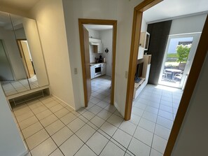 En modern lägenhet med kök, matplats och en balkong med utemöbler.