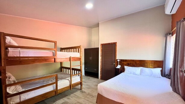 A room with bunk beds, a single bed, a wardrobe, and a nightstand. - Villa Noelia Garden Suite - Coatepeque Lake (Lago de Coatepeque)