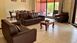 A living room with a sofa, a coffee table, and a dining area with chairs and a table. - Villa Noelia Paradise Suite - Coatepeque Lake (Lago de Coatepeque)