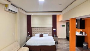 A hotel room with a large bed, a bedside table, a lamp, a sofa, a bathroom with a sink, and a mirror. - Villa Noelia Calli Suite - Coatepeque Lake (Lago de Coatepeque)