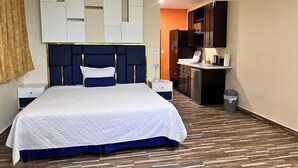 Een hotelkamer met een bed, nachtkastjes, een bureau en een kitchenette.