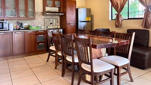 Una cucina con mobili in legno, un tavolo da pranzo con sedie e un frigorifero.
