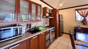 Una cucina con mobili in legno, un forno a microonde, un fornello e un frigorifero.
